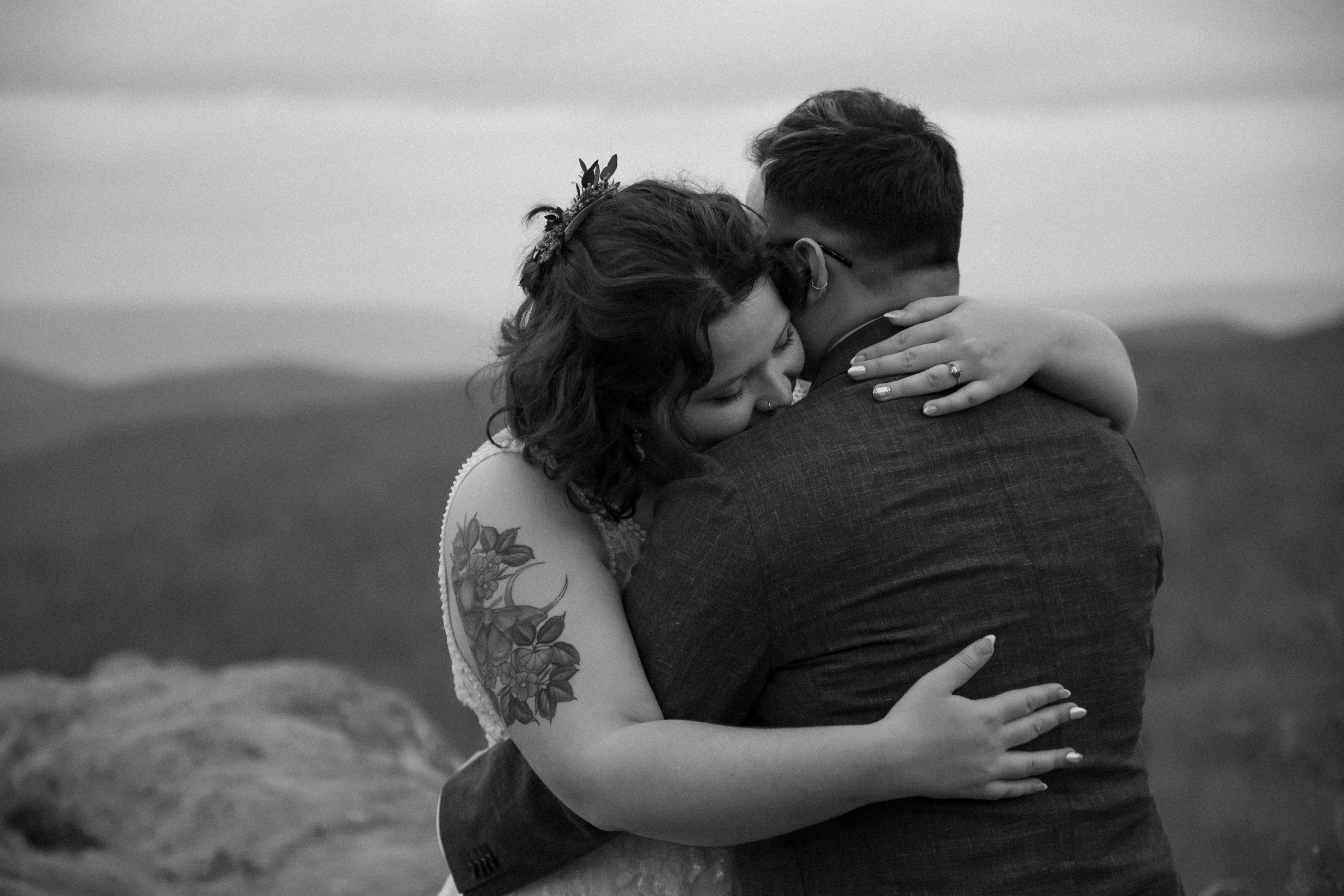 Black and white photo of couple embracing at a Shenandoah mountain overlook after their elopement ceremony