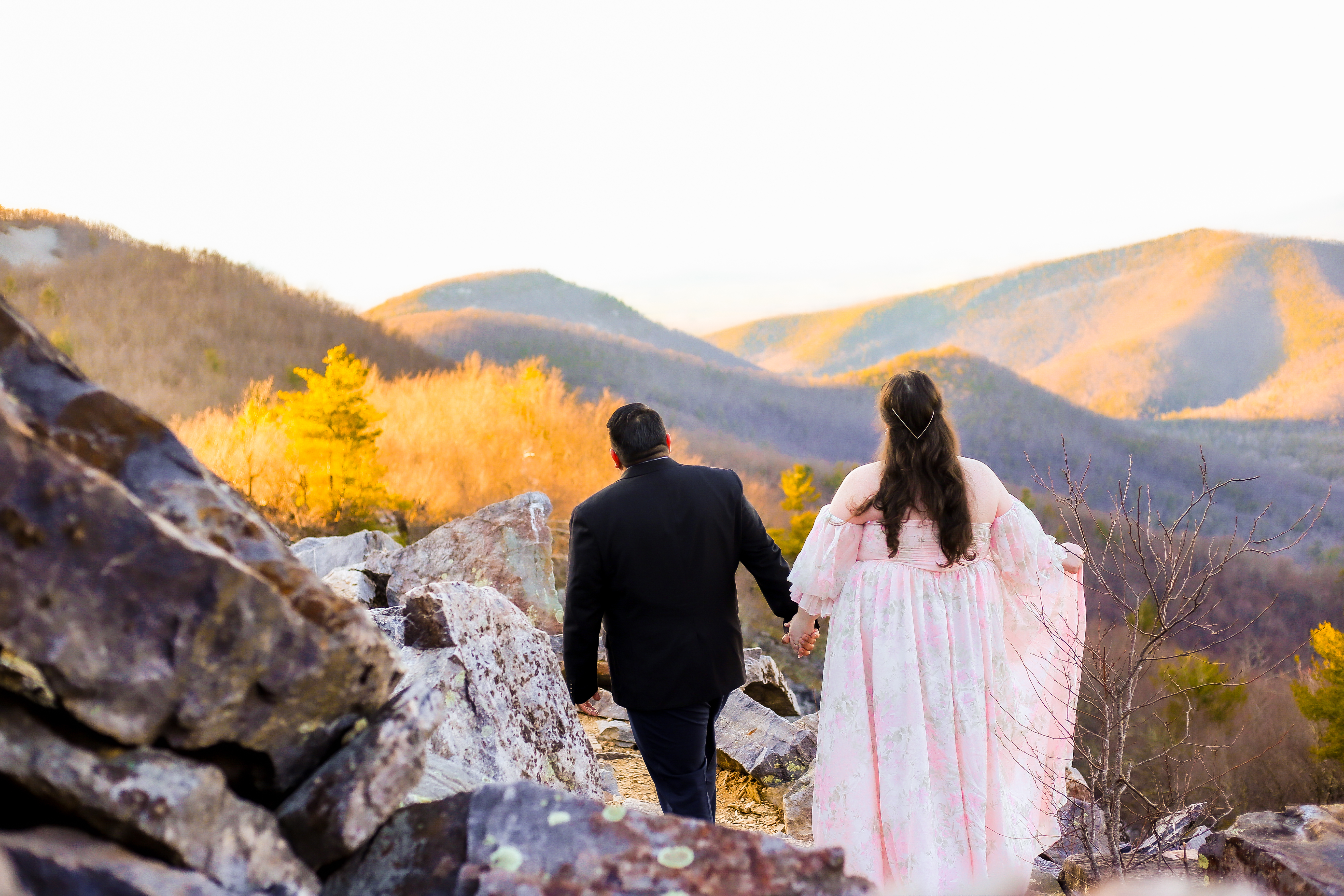 Couple walking among quartzite boulders at Blackrock Summit in Shenandoah National Park at golden hour